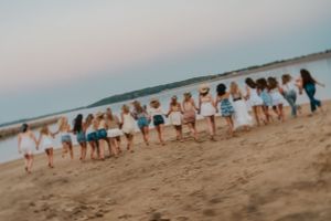 A slightly tilted and artistic photo of young ladies on a beach running toward the water. They are holding hands
