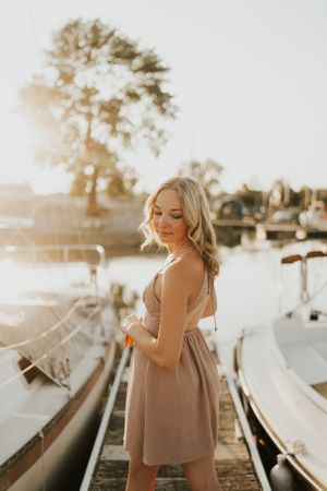 A young lady posing for a photo at sunset on a boat dock.
