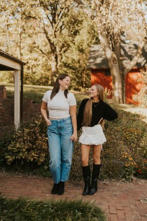Two best friends holding hands and smiling at each other.