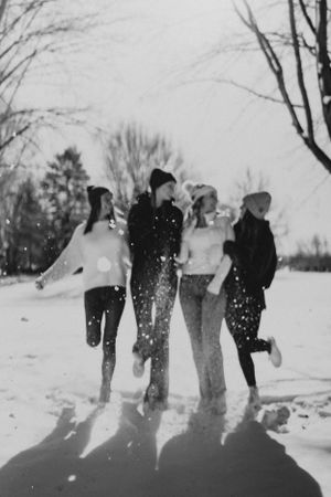 A group of teenagers holding hands while playing in the snow.
