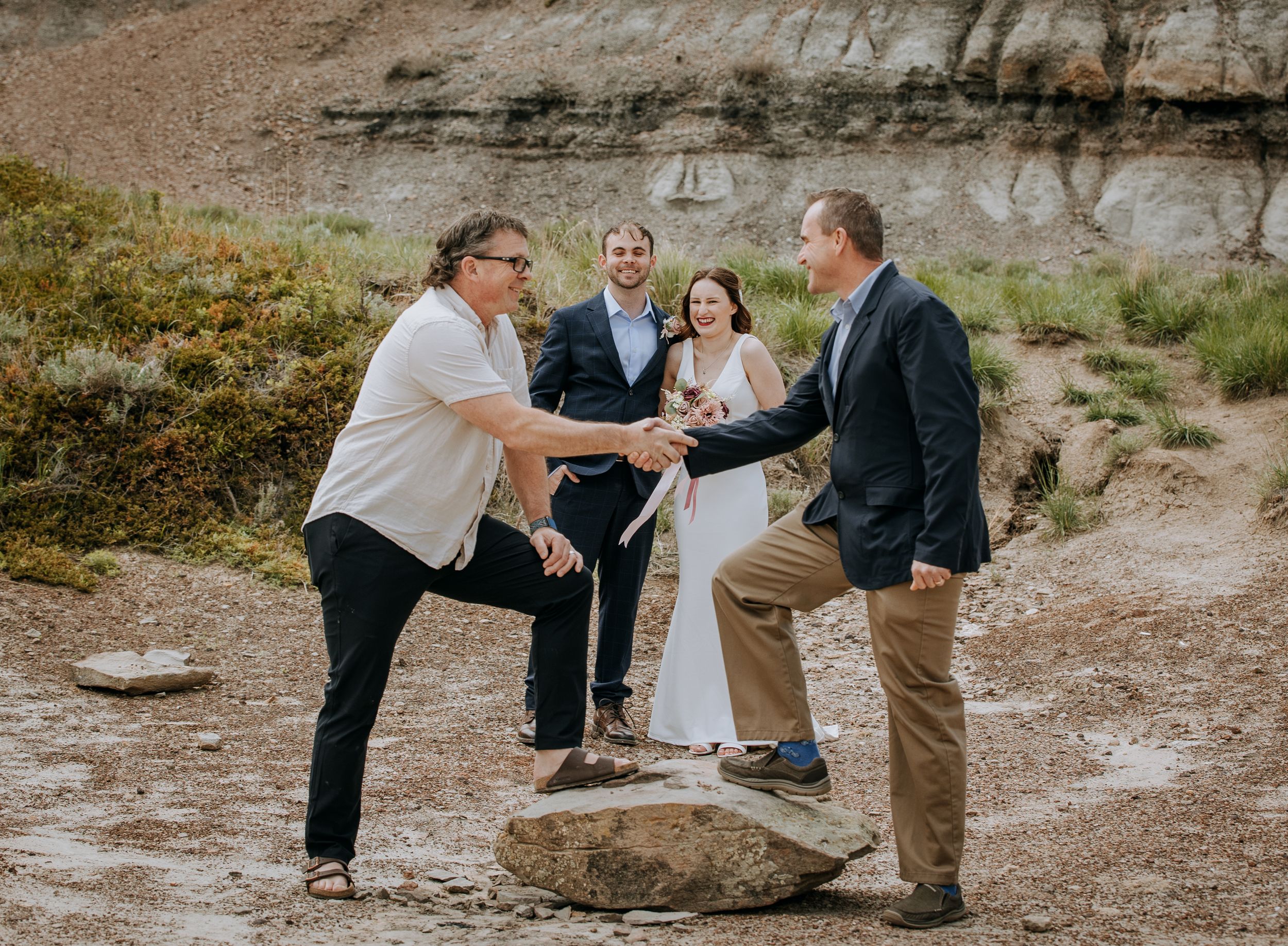 Group gathers around rock formation during outdoor ceremony.