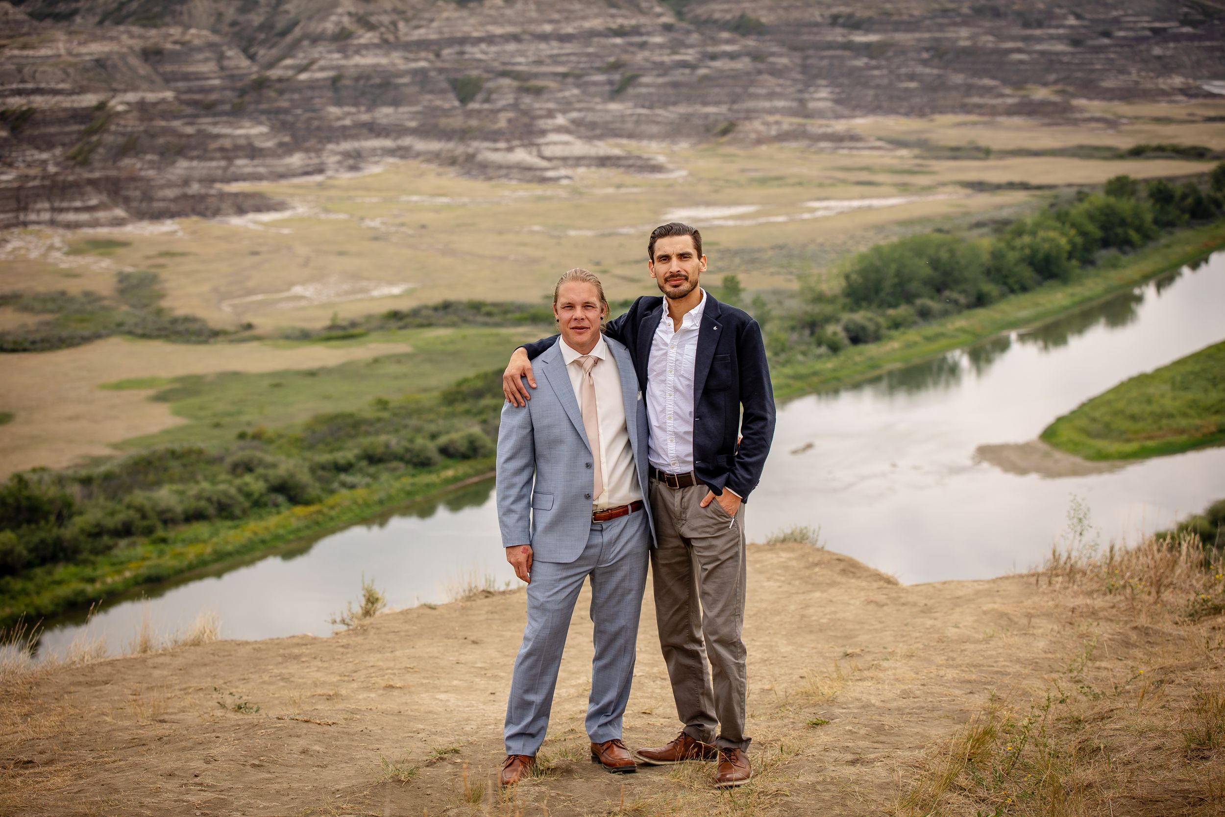 Two people stand together overlooking scenic river valley landscape.