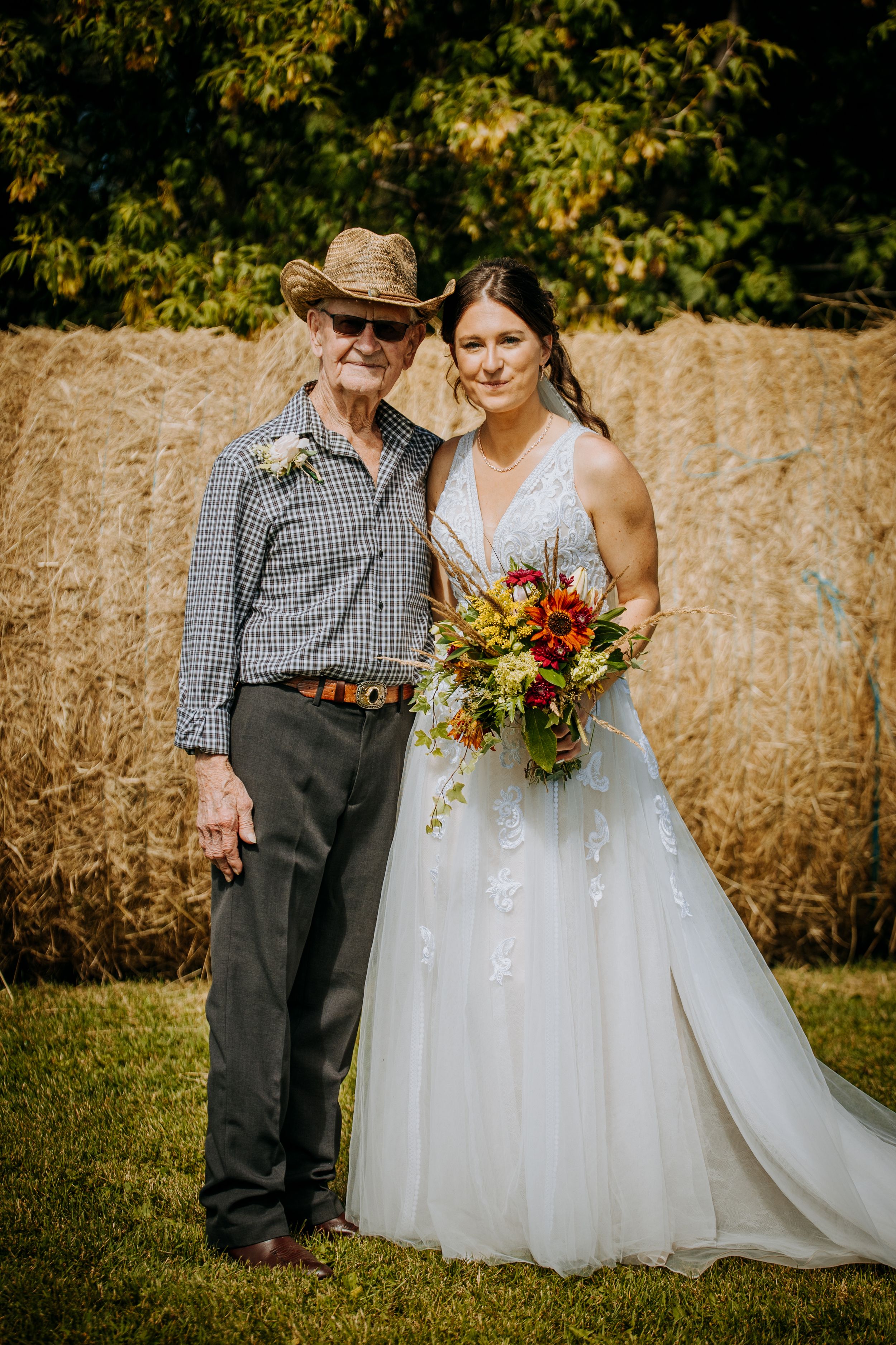 Rustic wedding portrait with autumn colors and hay bale backdrop.
