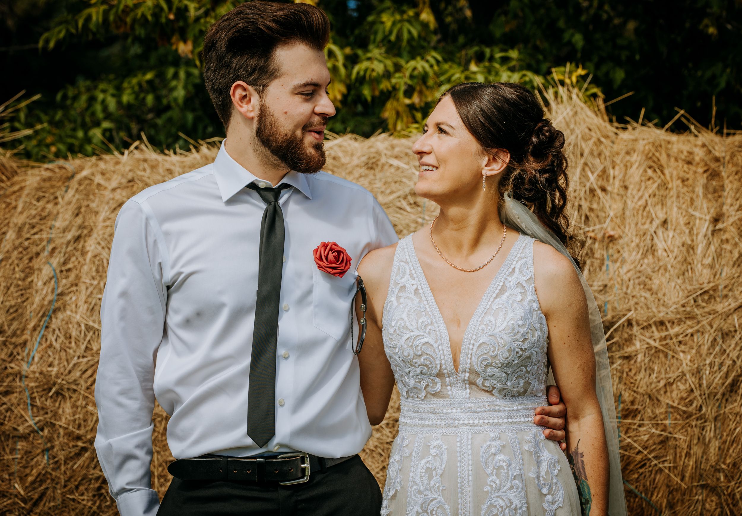 Romantic wedding portrait against rustic hay bale background with soft natural lighting.