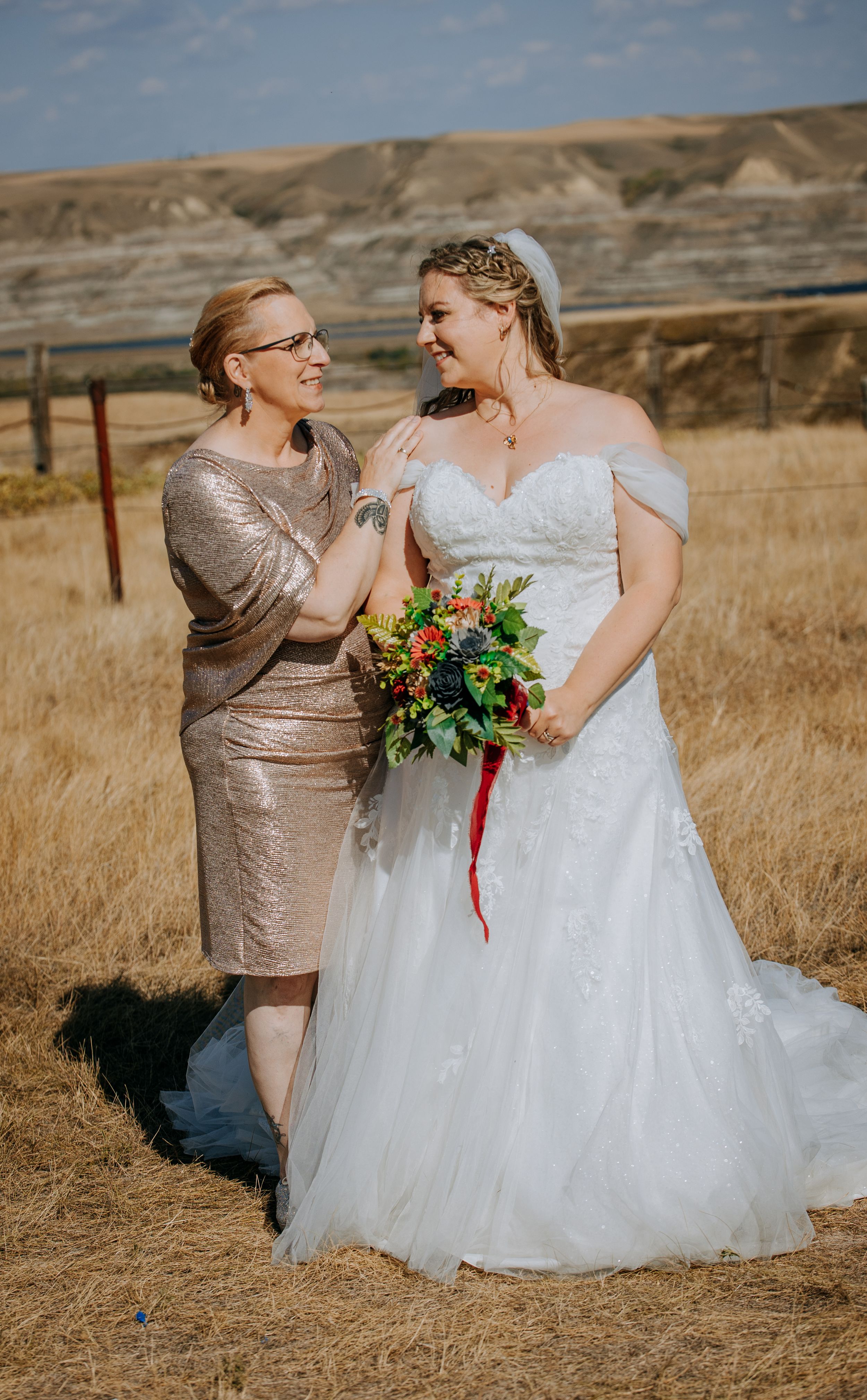 Wedding portrait featuring a sequined dress and white gown against a desert landscape.