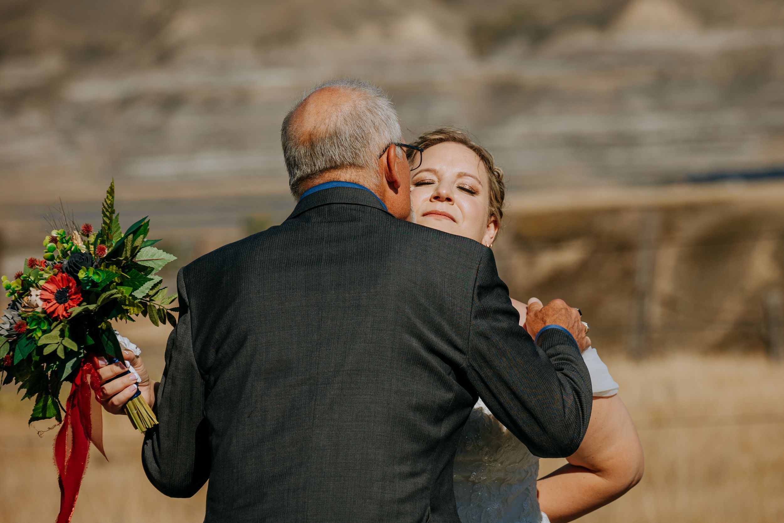 Emotional embrace captured during outdoor wedding ceremony.