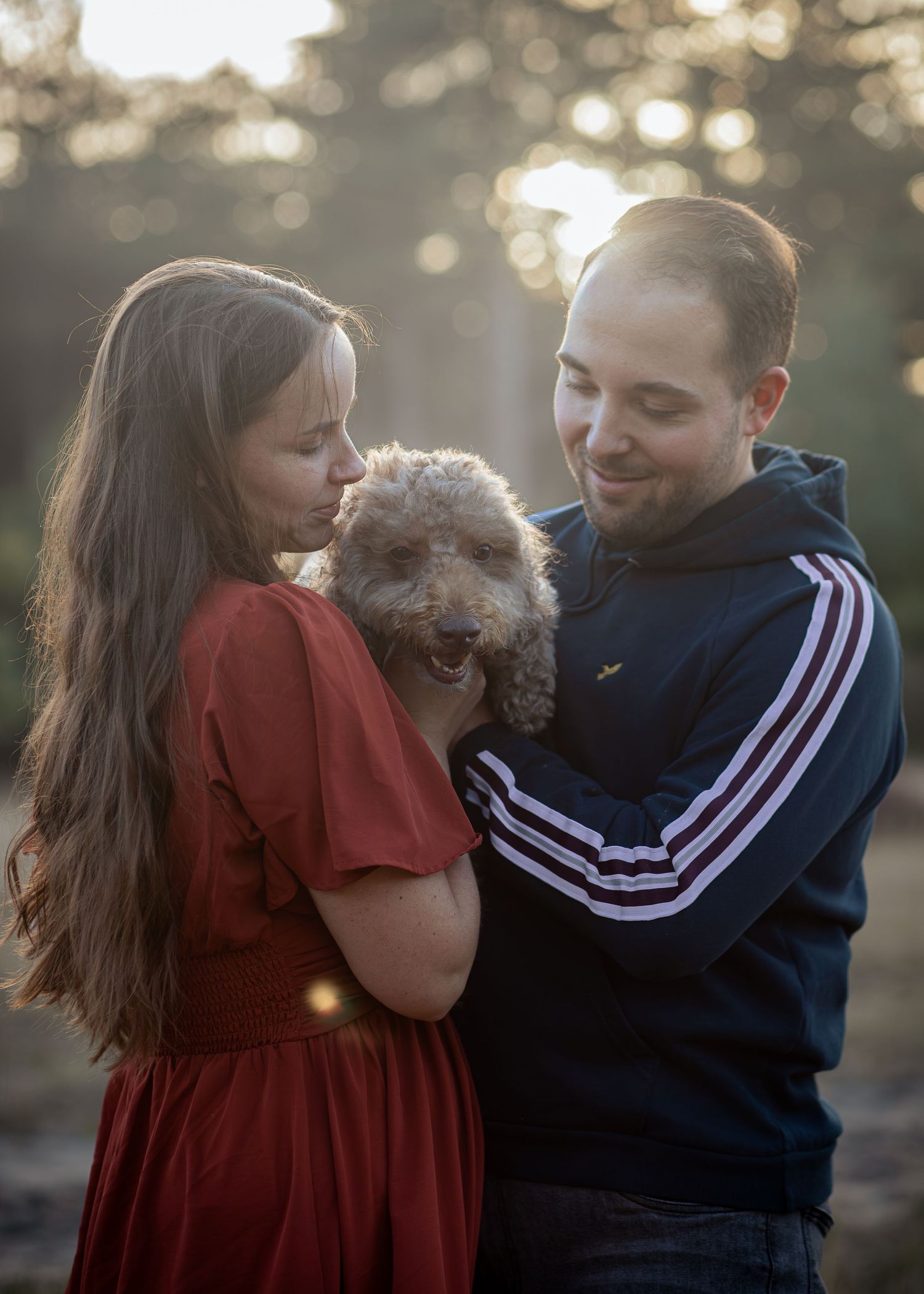 Koppel met hond met zonsondergang tijdens golden hour in het bos.