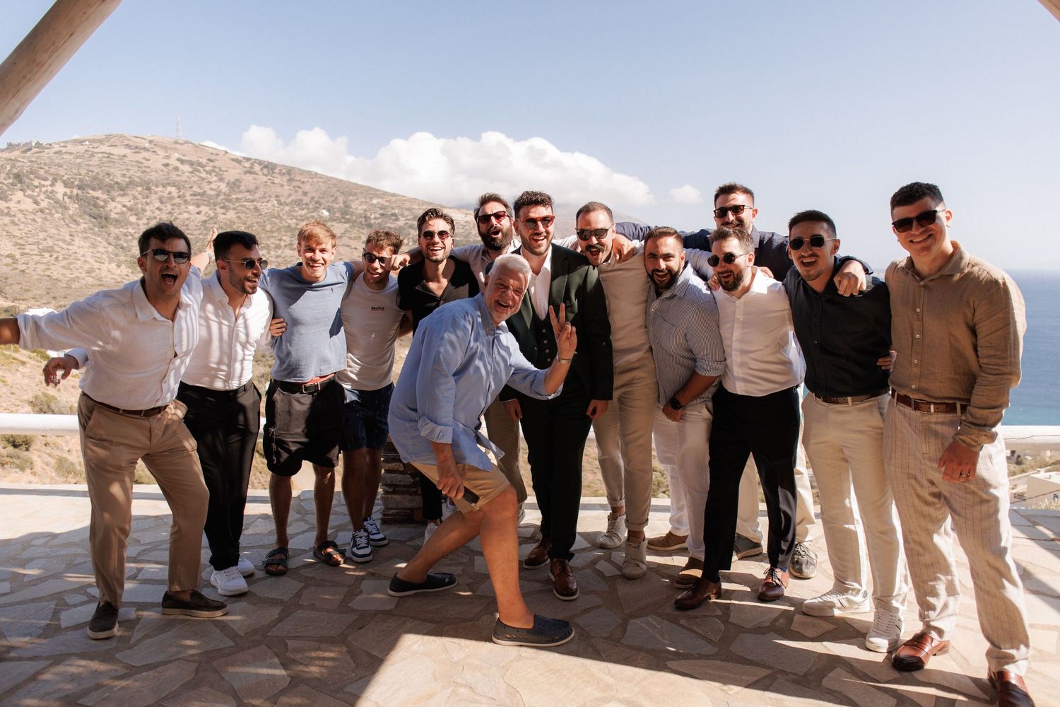 A group of people posing together on a stone terrace overlooking desert mountains and blue sky.