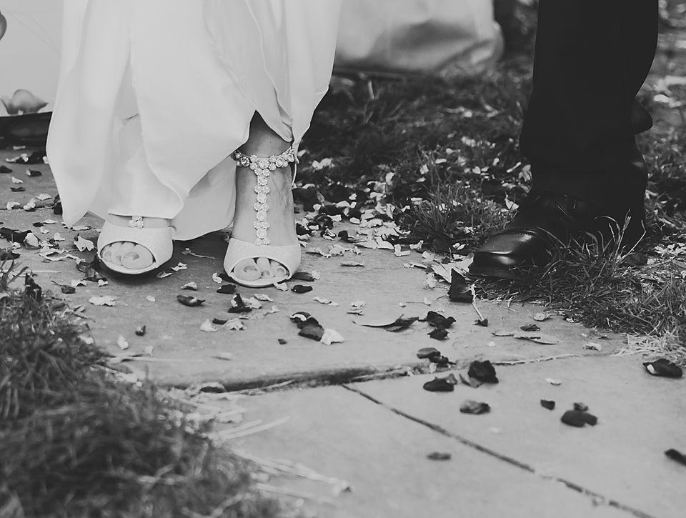Wedding guests walking outdoors with scattered petals on the ground.