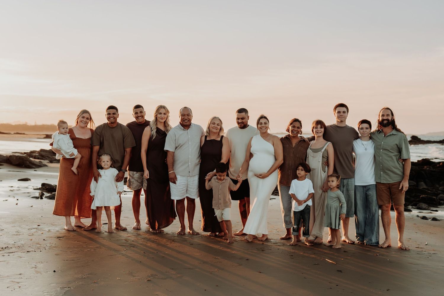 Group photo of people lined up on gladstone beach at sunset wearing coordinated outfits.