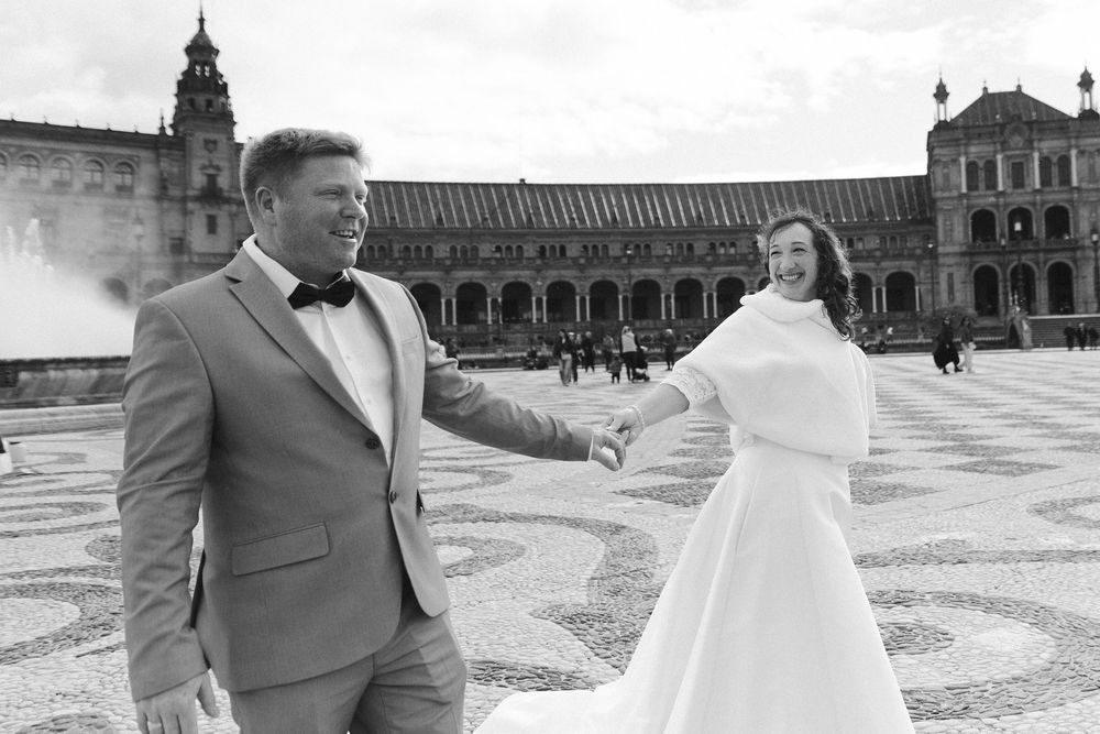 A couple shares a romantic moment while posing for wedding photos in front of Plaza de España in Seville, Spain.