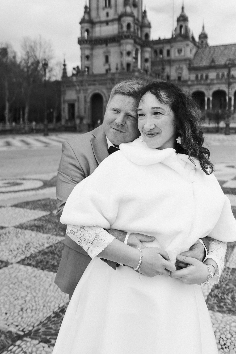 A couple shares an intimate moment in front of an ornate church building with domed architecture in the background.