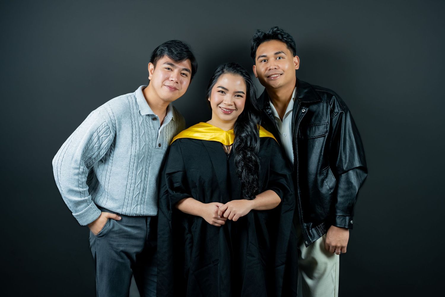 Three people pose together in a series of casual black and white studio portraits showing playful interactions.