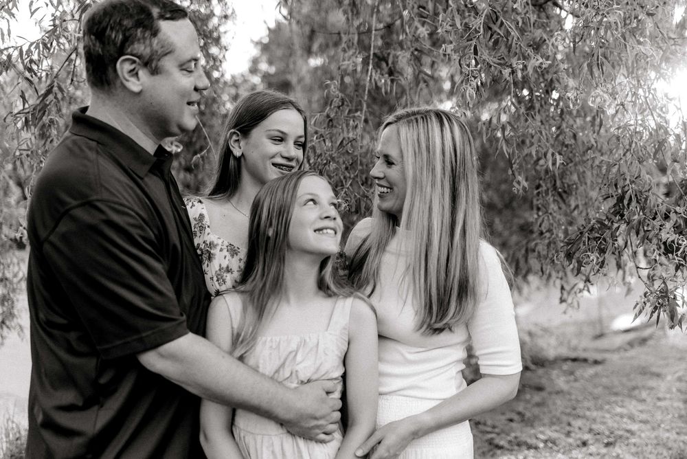 Family laughing in black and white under willow tree in Pittsburgh, PA