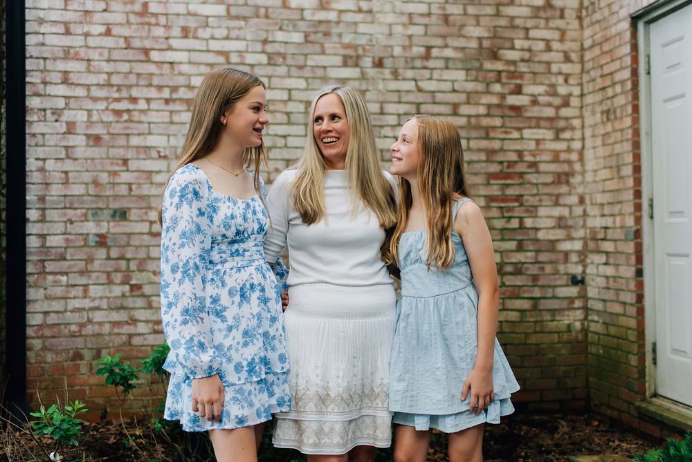Mom and daughters laughing in front of brick wall in Pittsburgh, PA