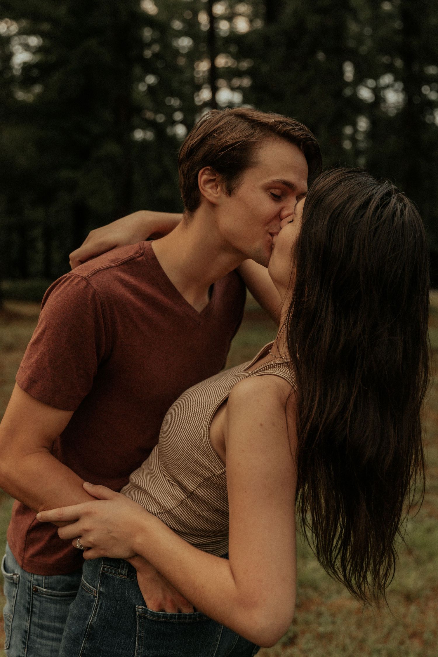 An intimate moment between a couple in a wooded outdoor setting.