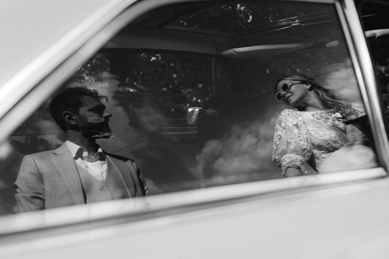 A romantic black and white wedding photograph showing a tender embrace in a natural outdoor setting.