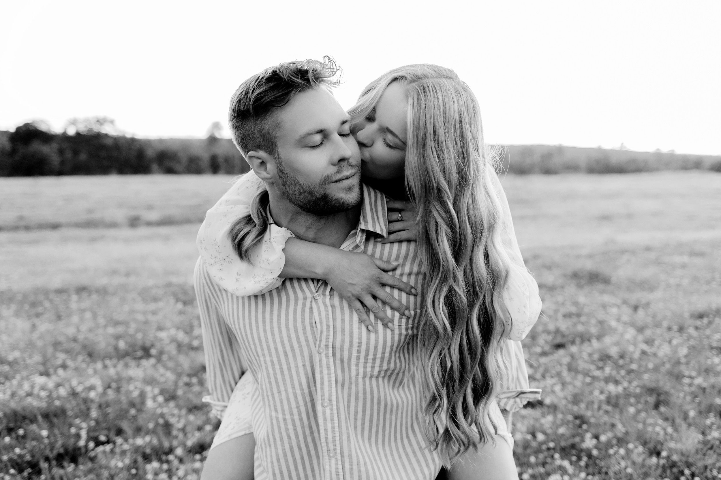 Parfotografering med Martina och Sebastian i Borgvik utanför Karlstad. Hon sitter på hans rygg och pussar honom på kinden.