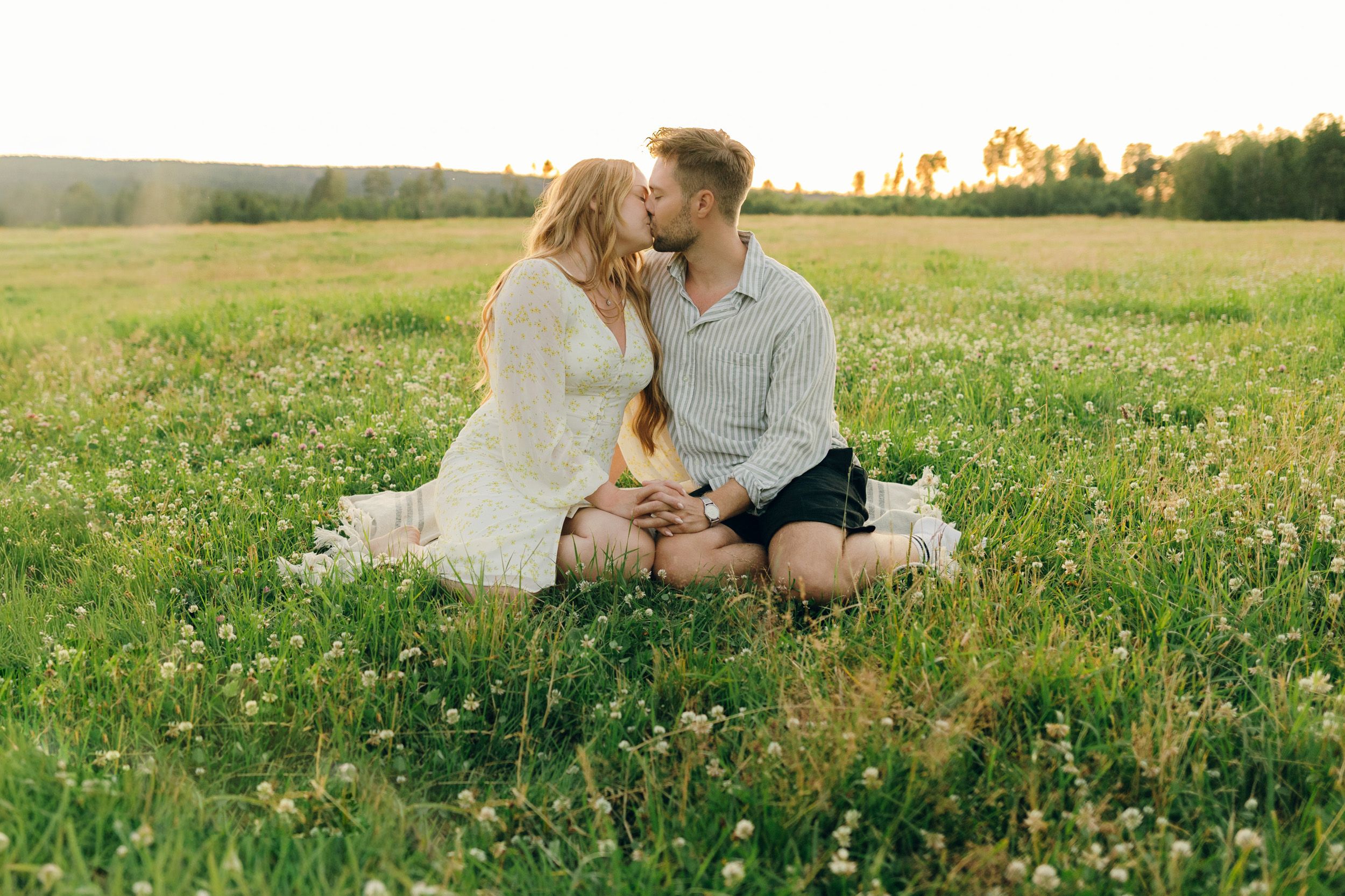 Parfotografering med Martina och Sebastian i Borgvik utanför Karlstad. Sitter på en filt tillsammans på ängen. Lutar in mot varandra.