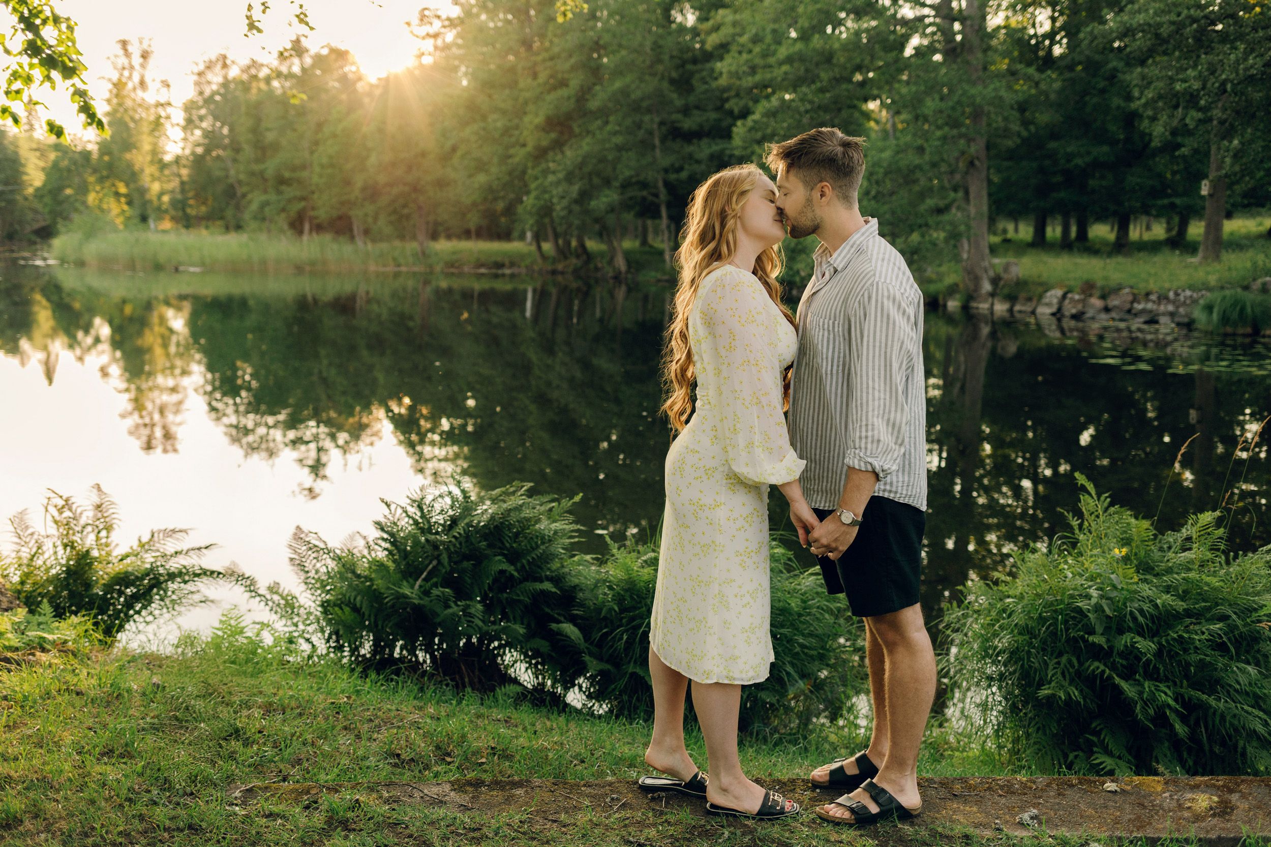 Parfotografering med Martina och Sebastian i Borgvik utanför Karlstad. Står framför sjö, håller hand och lutar sig mot varandra.