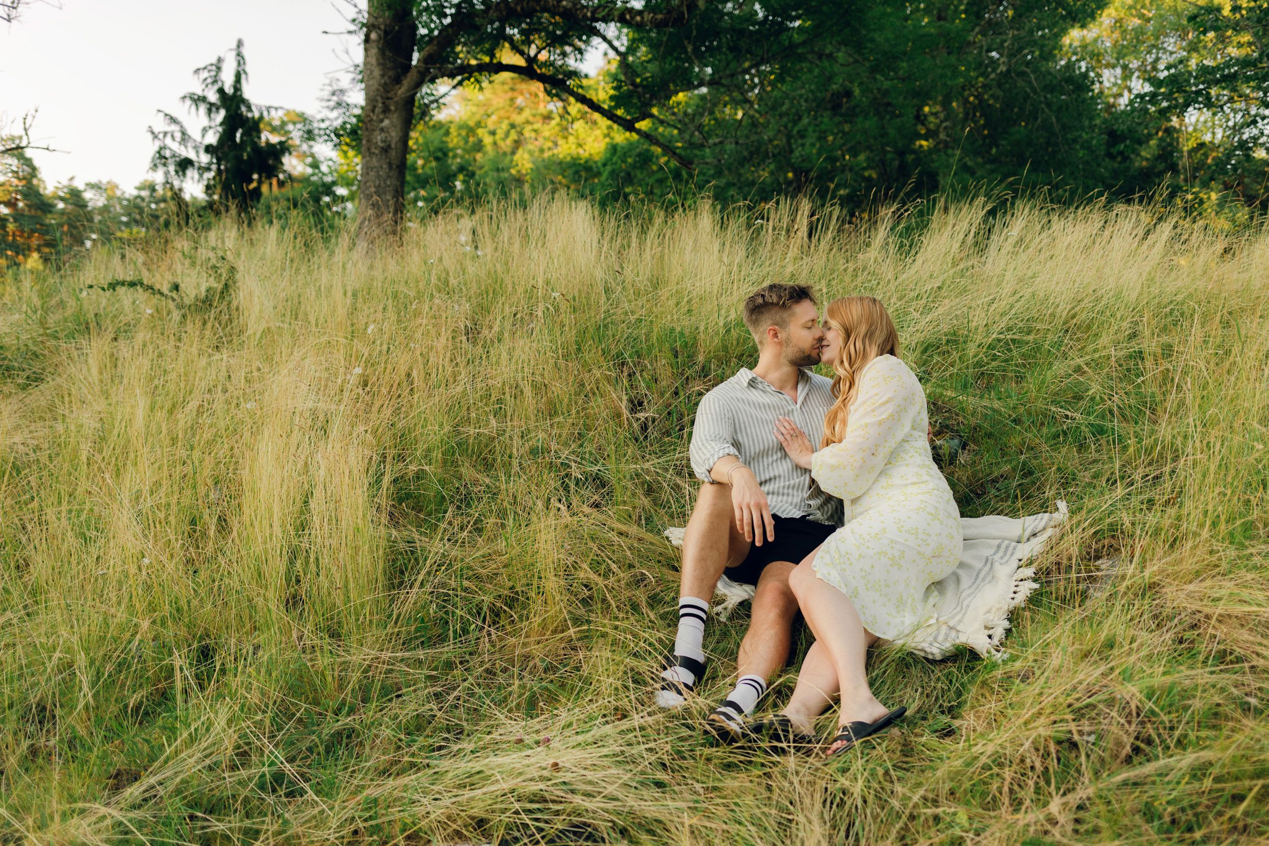 Parfotografering med Martina och Sebastian i Borgvik utanför Karlstad. Sitter på en filt tillsammans i högt gräs.