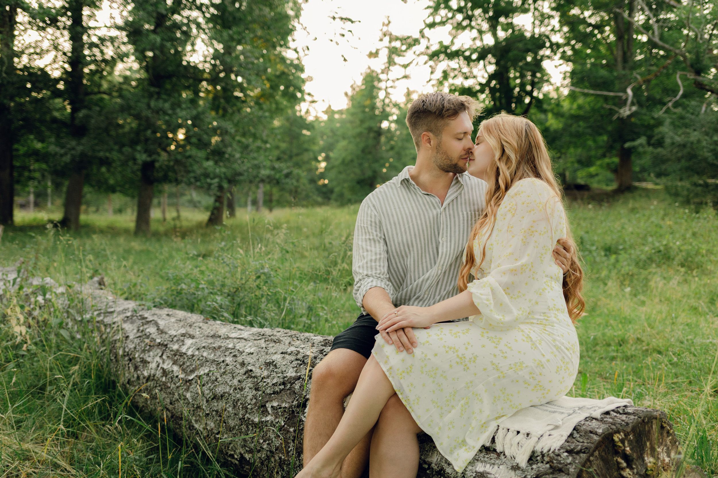 Parfotografering med Martina och Sebastian i Borgvik utanför Karlstad. Sittandes tillsammans på ett fallet träd. Ansiktena nära varandra.