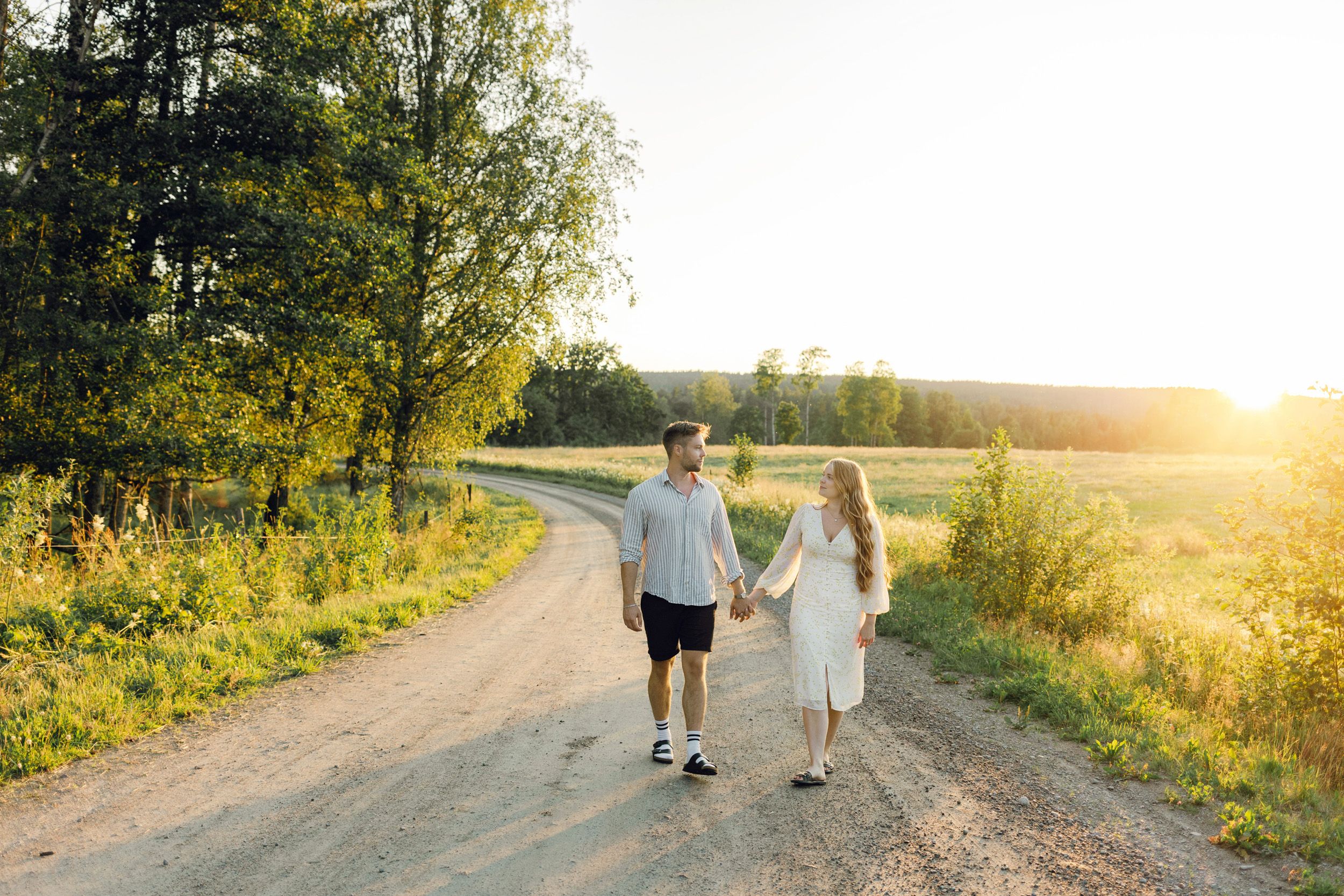 Parfotografering med Martina och Sebastian i Borgvik utanför Karlstad. Gående på grusväg i solnedgång.