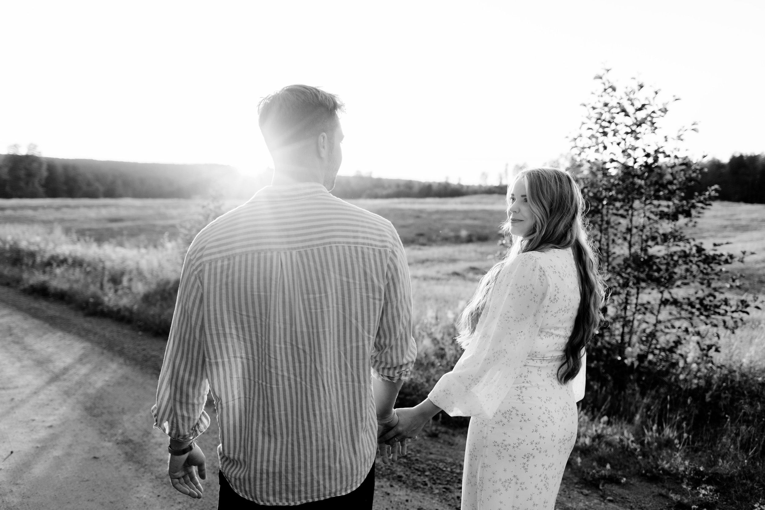 Parfotografering med Martina och Sebastian i Borgvik utanför Karlstad. Gående på grusväg i solnedgång. Hon tittar på honom.