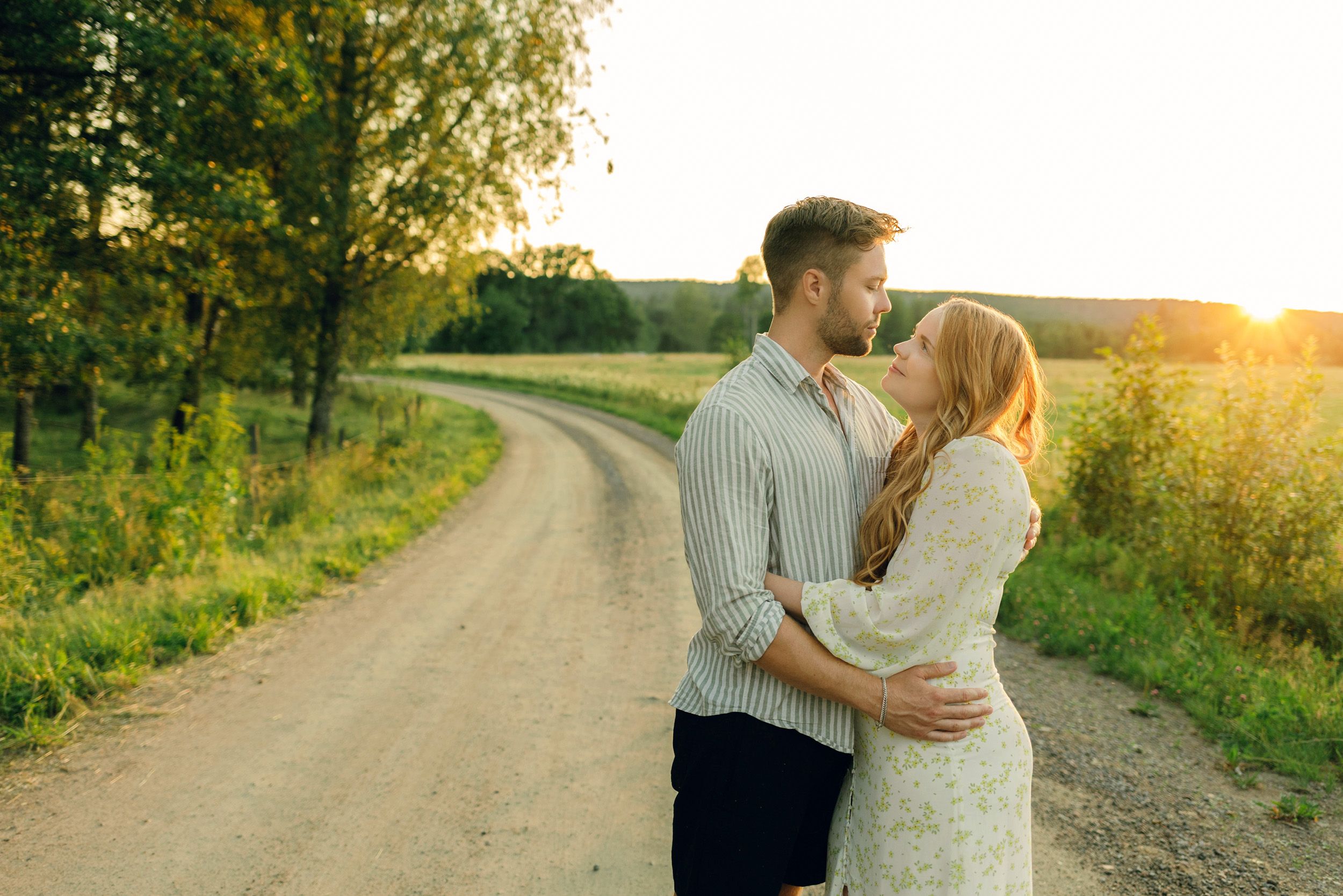 Parfotografering med Martina och Sebastian i Borgvik utanför Karlstad.Stående på grusväg i solnedgång. Tittar på varandra.