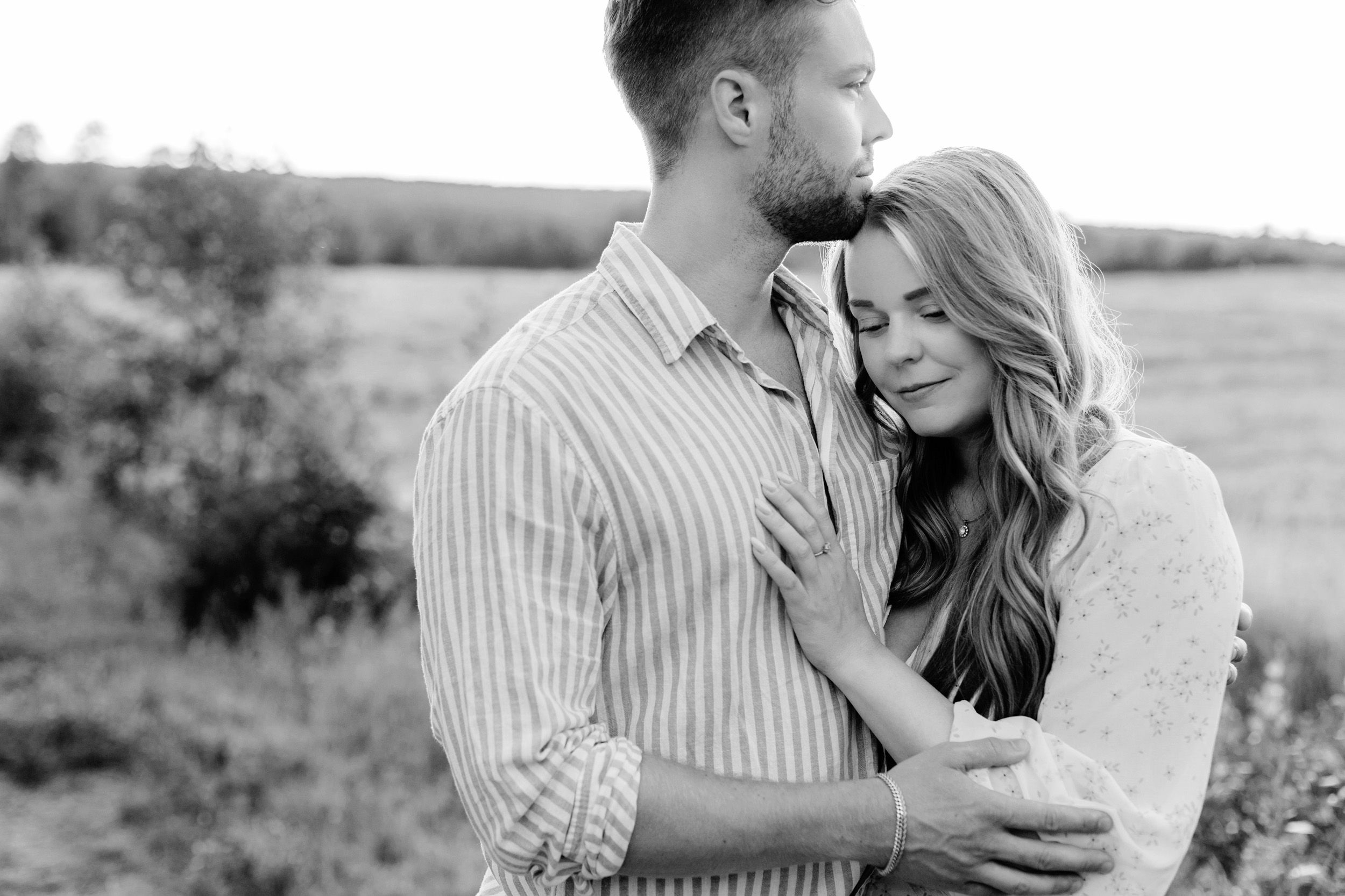 Parfotografering med Martina och Sebastian i Borgvik utanför Karlstad. Stående på grusväg i solnedgång. Svartvitbild de håller om varandra.