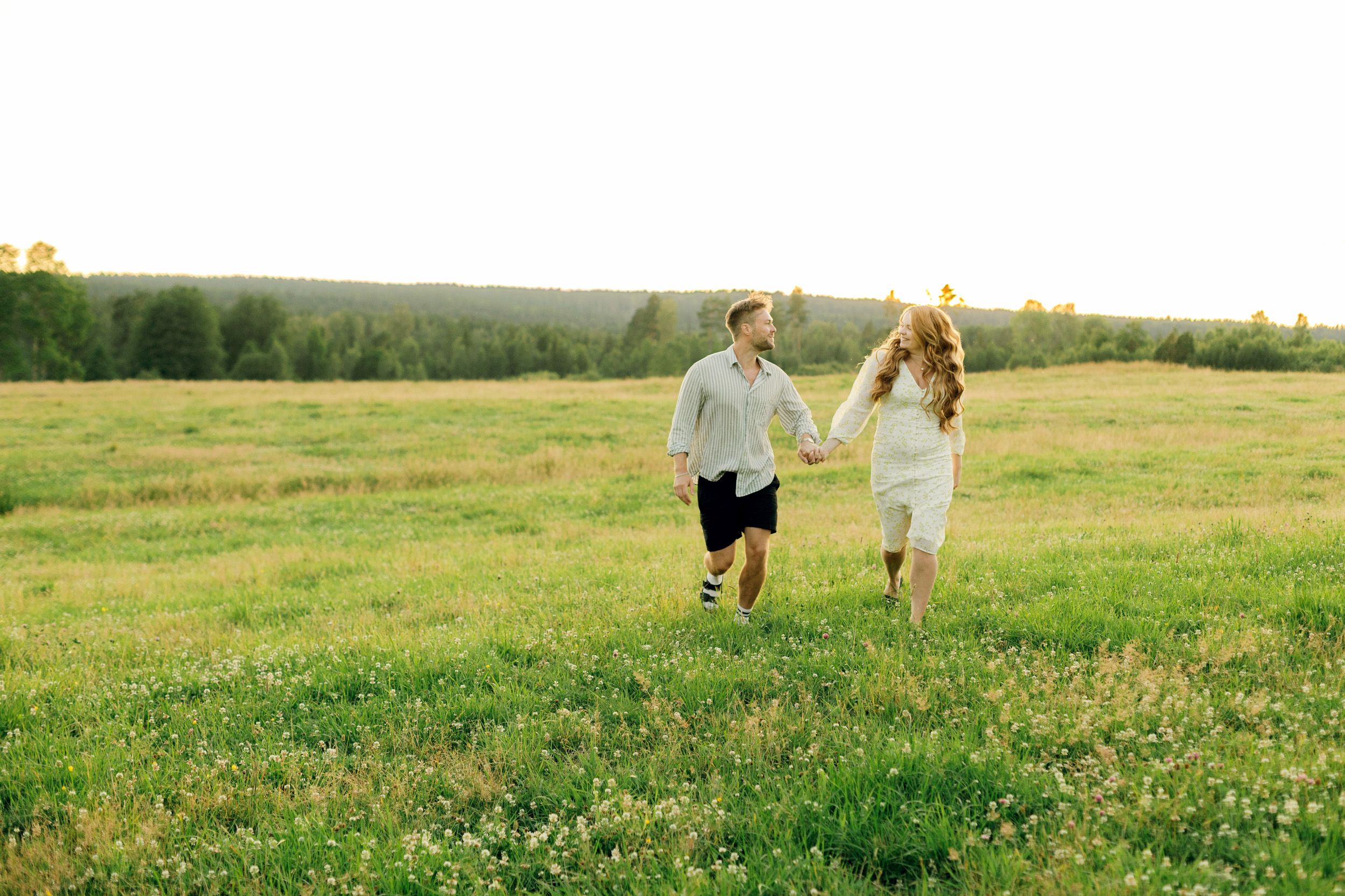 Parfotografering med Martina och Sebastian i Borgvik utanför Karlstad. De springer på en äng tillsammans hand i hand.