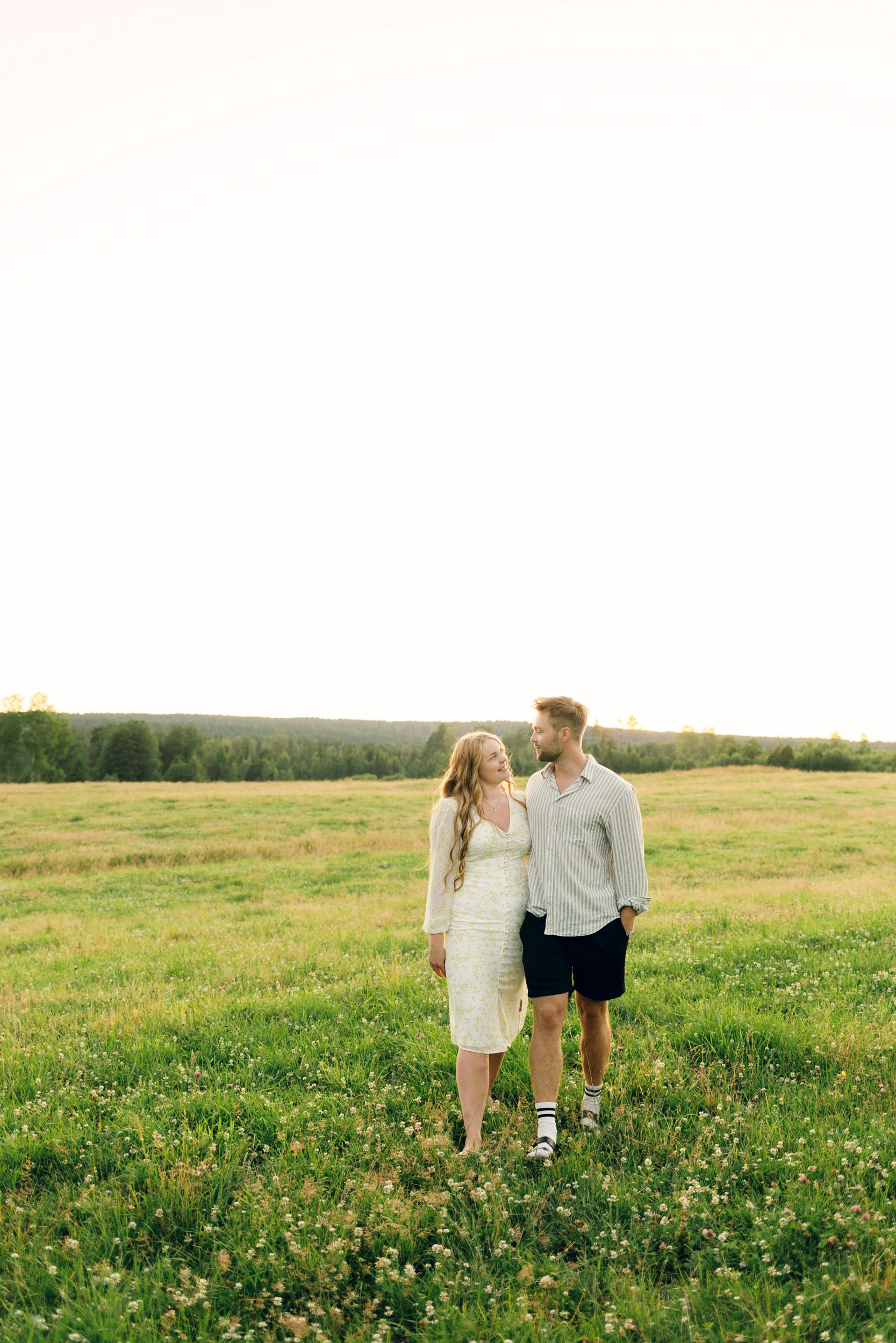 Parfotografering med Martina och Sebastian i Borgvik utanför Karlstad. Håller om varandra och går mot kameran på ängen.
