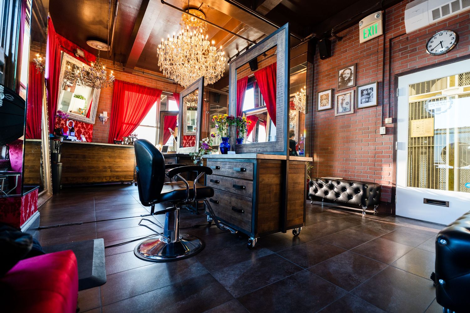 Stylish vintage barbershop interior with red curtains, crystal chandelier, leather chair and exposed brick walls.