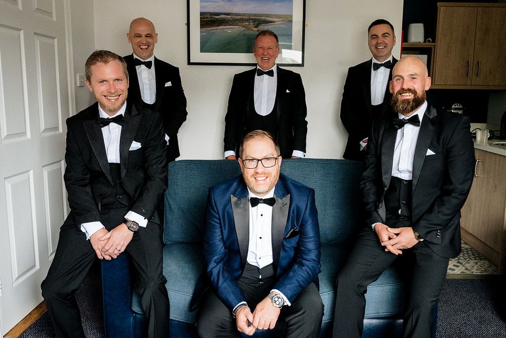 Wedding party members in formal attire gathered in a room before the ceremony.
