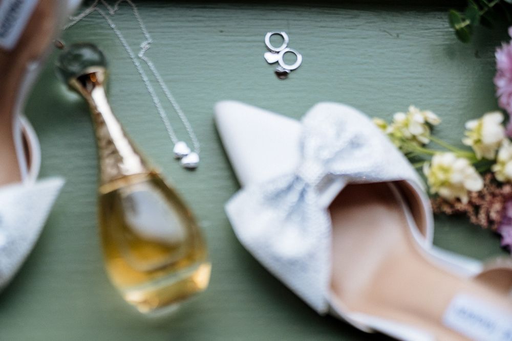 Wedding rings and delicate floral arrangements displayed on a soft gray surface with natural lighting.