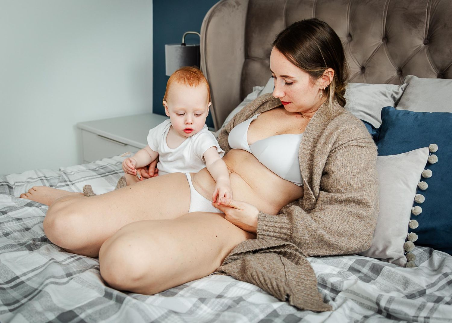 A mum and her toddler relax and cuddle on the bed at home during a Bristol motherhood photoshoot for caesarean section awareness.