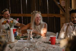 Wedding guests enjoying dinner and conversation at rustic wooden tables with candlelight.