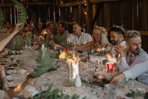 Wedding reception tables decorated with candlelight and greenery in a cozy barn setting.