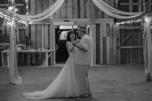 Wedding party celebrates in an elegant indoor venue with decorative white draping and string lights.