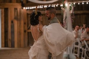 String lights illuminate a rustic barn wedding reception with dancing guests.