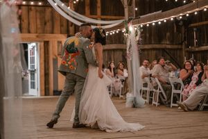 Wedding celebration in a barn venue with string lights and guests watching the newlyweds dance.