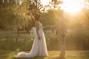 Wedding couple silhouetted against golden sunset in outdoor garden setting.