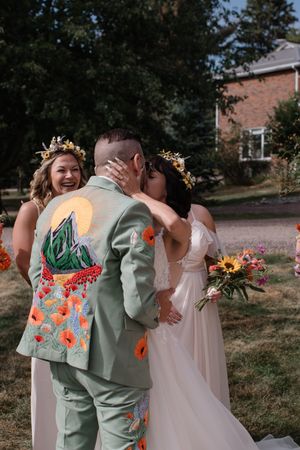 Wedding party members in sage green and floral attire sharing joyful moments during outdoor photo session.