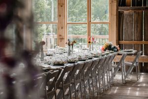 Rustic barn wedding reception venue with rows of wooden chairs and elegant table settings.