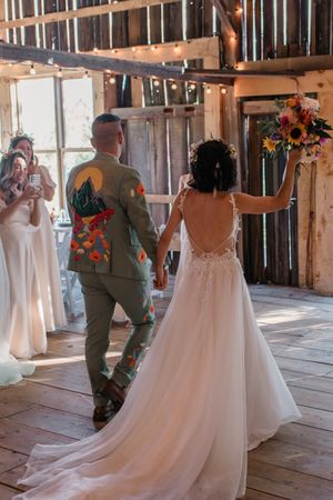 A wedding couple shares their first dance in a rustic wooden barn decorated with flowing white drapery.