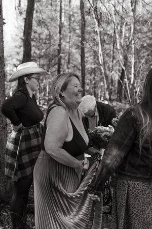 A sequence of black and white photos showing two people laughing and embracing in a forest setting.