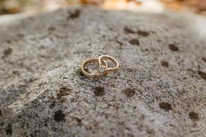 Wedding rings rest on a textured stone surface creating an elegant minimalist composition.