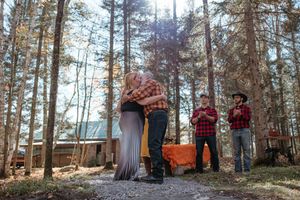 Family enjoying a playful outdoor photoshoot session in a sunlit forest with pine trees.