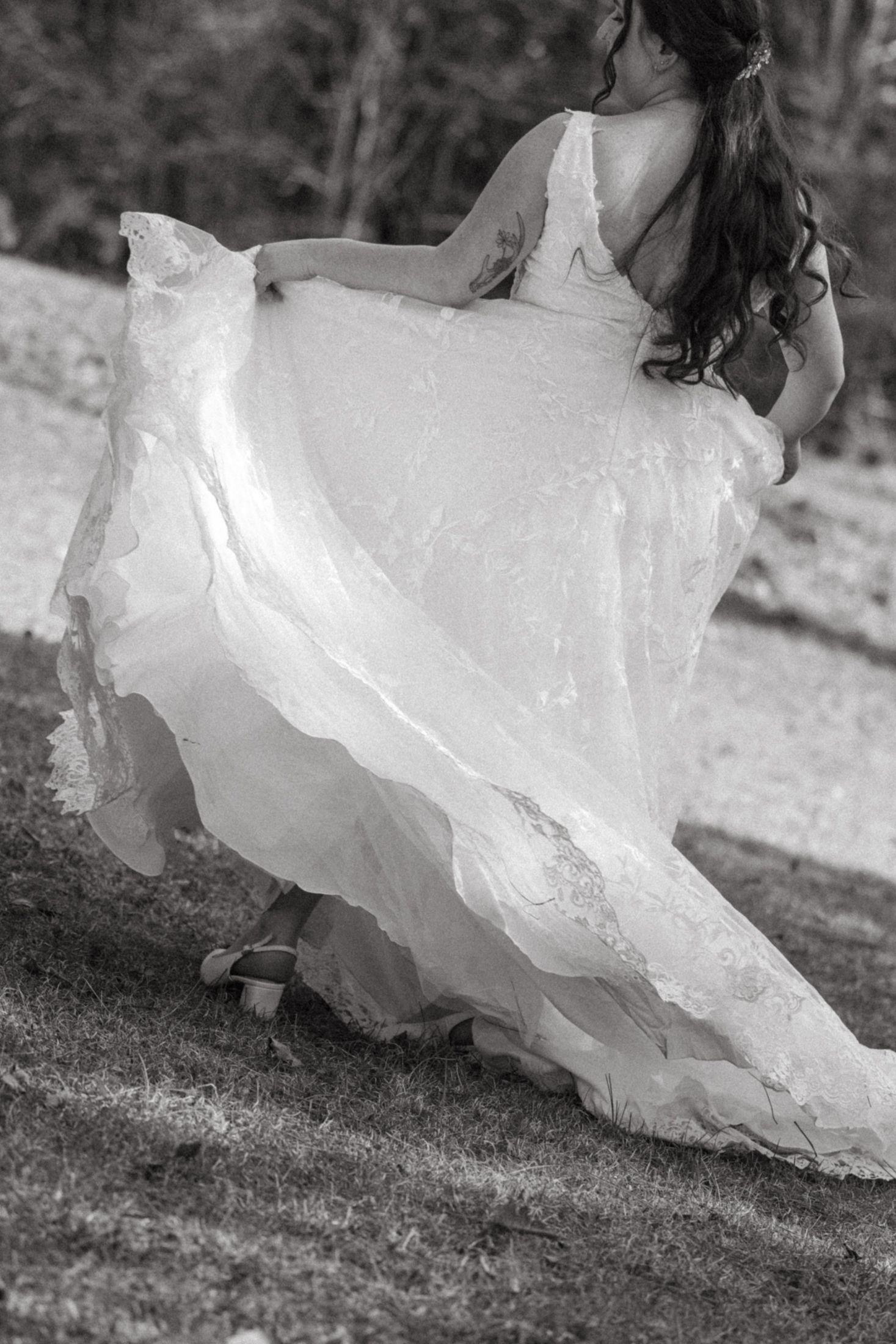 Close-up details of a flowing white wedding dress skirt moving gracefully against a natural outdoor background.