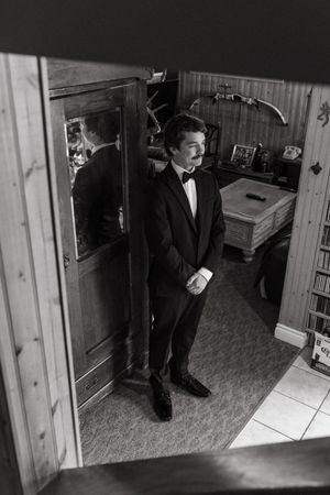 A sequence of black and white surveillance camera footage shows someone in formal attire walking through an interior space.